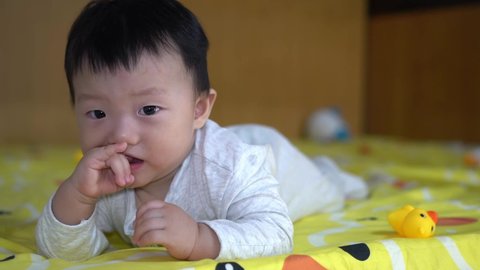 Baby chinese boy chew the hand. Drooling kid