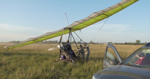 Berdsk, Siberia, Russia, August 28.2021 Field airfield. Elderly technicians roll out a hang glider with an engine on the runway.
