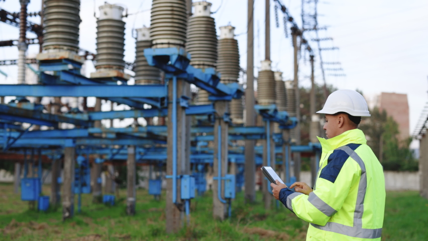 Electrical worker engineer working with digital tablet near tower with electricity. Energy business technology industry concept. Electrical engineer studying reading on tablet | Shutterstock HD Video #1079155655