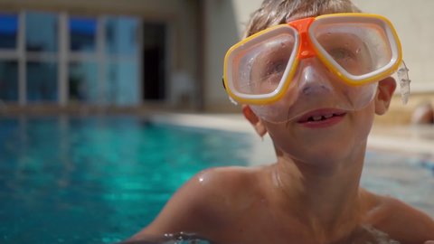 cute boy in a scuba diving mask is swimming in pool. Summer holidays. Rest at the hotel. School holidays. A child on the background of beautiful clear water in a swimming pool. Rest, fun, pleasure