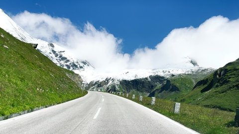 GROSSGLOCKNER, AUSTRIA - SEPTEMBER 1st, 2021: Driving along major road of Grossglockner National Park in summer season with mountains covered by snow