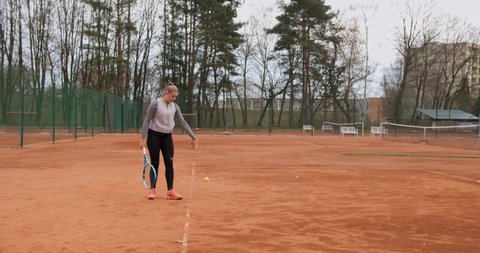 Olomouc , Czech Republic - 06 09 2021: Professional young female tennis player trains serve on tennis field outdoors,static medium shot