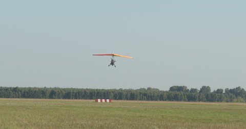 Gliding, training flights. A hang glider with a pilot and a passenger is lowered to land at the airfield. Shooting with hands (hand-helding) Siberia.