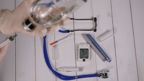 Close-up of a female doctor with a syringe and an ampoule of medicine in her hands in the hospital against the background of a glucose meter and insulin. Treatment of diabetes.