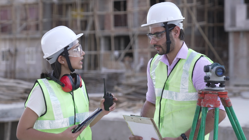 Indian forewoman and senior architect talking together with site plans at construction site outdoors.contractor worker in hardhat discussion with female  leader.group of diversity builder. Royalty-Free Stock Footage #1079168738