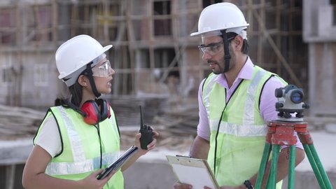 Indian forewoman and senior architect talking together with site plans at construction site outdoors.contractor worker in hardhat discussion with female  leader.group of diversity builder.