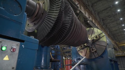 Manufacturing of Heavy Duty Gas Turbines. Rotating Compressor Component Fixed on a Big Testing Machine. Machining Process. Operator supervising the Work. Inside a Production Facility. Heavy industry.