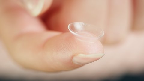 Close-up of a transparent eye lens on finger, decorative lenses. Optical shop concept. Advertising of contact daily lenses for make-up and performances, halloween. 