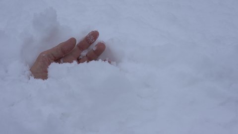 Human hand in a snowdrift after an avalanche. The person stuck in the snow is still alive and needs help.