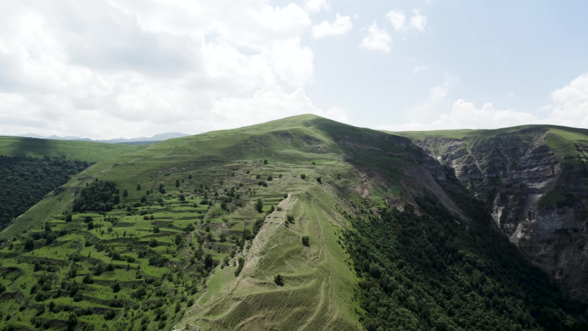 Majestic mountain aerial landscape with pine forest on a summer sunny day. Action. Green mountain ridge on cloudy sky background, Alps.