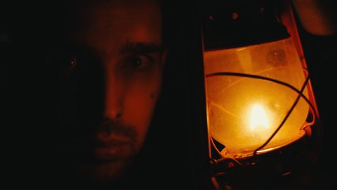 A man's face in the dark close-up illuminated by a kerosene lamp. Halloween Concept