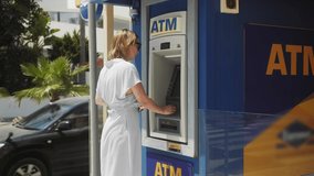 Woman getting money from an ATM cash machine with a credit card on city street. - Powered by Shutterstock - Get 15% off with code: PIKWIZARD15