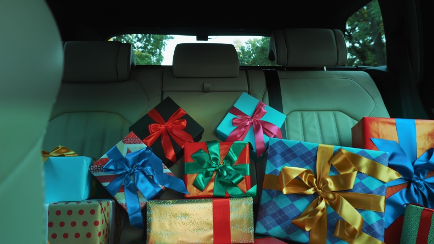 gift boxes in car. delivery. donation, charity. many beautifully wrapped parcels, boxes, lie in car back seat, in sunrays. close-up, view from inside car. Christmas presents. Online order.