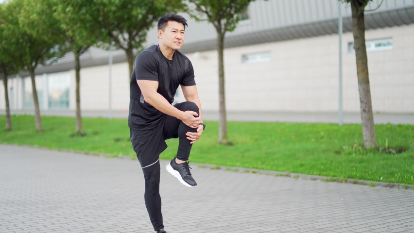 Young asian runner athlete with muscle pain. Man massaging Stretching, trauma injury while jogging outdoors. Fitness male sprain severe pain stretch pull. Leg muscle cramp calf sport | Shutterstock HD Video #1079191247