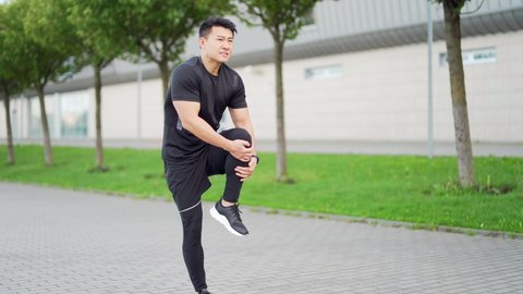 young asian runner athlete with muscle pain. Man massaging Stretching, trauma injury while jogging outdoors. Fitness male sprain severe pain stretch pull. Leg muscle cramp calf sport