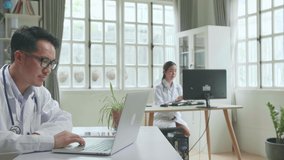 Asian Male Doctor Communicates With Patient By Video Link, Doctor Consults Patient Using Modern Technologies, Using Laptop Computer In Workplace
