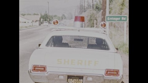 1970s: Police car sits on side of road. Teenage boys ride in back of van. Cop checks list of stolen cars. Man uses radio. Cops chase van.