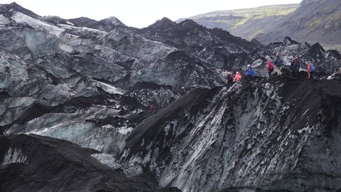 People hiking on an Icelandic glacier (Sólheimajökull). Solheimajokull glacier (part of Myrdalsjokull) in Iceland. Solheimajokull melting glacier ice.