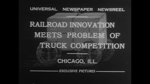 CIRCA 1931 - A train is used to transport trucks across Chicago, Illinois.