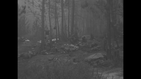 CIRCA 1944 - American paratroopers rest on a forest floor in France, one of them using a parachute as a blanket.