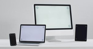 Video of laptop, smartphone, tablet and computer on white table with copy space in office. technology, business, work station, home office concept.
