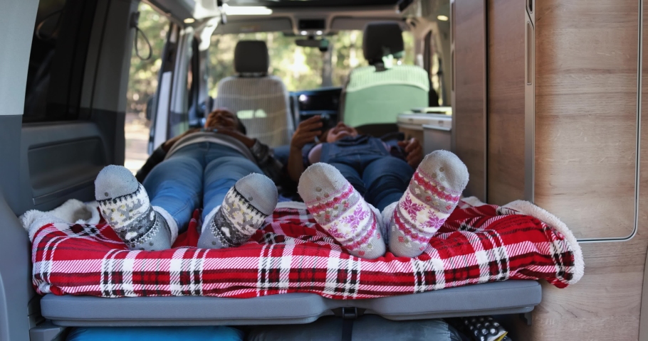 Multiracial senior women realx inside mini van camper wearing cozy socks 