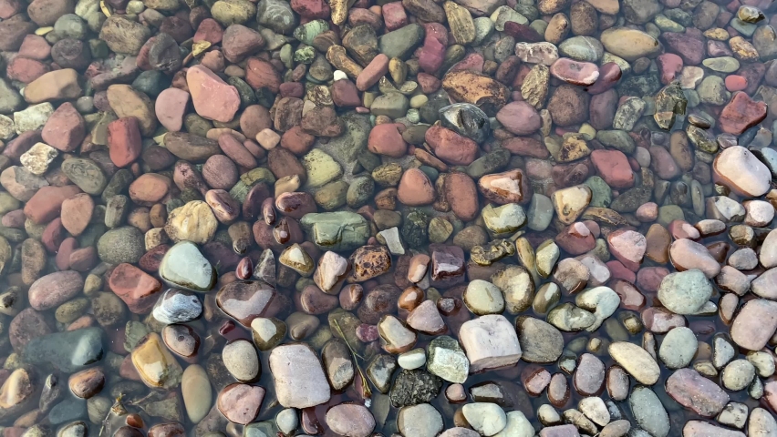 Panning shot of the colorful pebbles and rocks of Lake McDonald in Glacier National Park