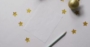 Video of christmas decorations and stars with white card on white background. christmas, tradition and celebration concept.