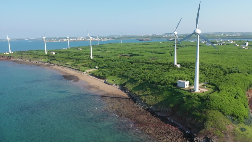 Aerial view of giant wind turbines standing in the green field by the beach in a seaside park along the beautiful coastline on a sunny summer day, in Zhongtun, Baisha Township, Penghu County, Taiwan | Shutterstock HD Video #1079213690