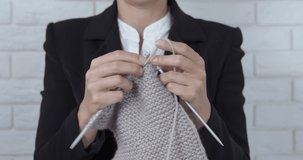 Knitting in the office. A view of knitting woman hands in office suit in the room.