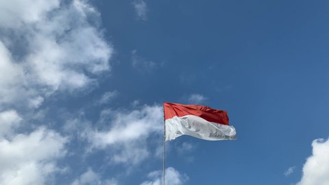 Indonesia and Monaco national flag with white cloudy sky background, in moderate wind