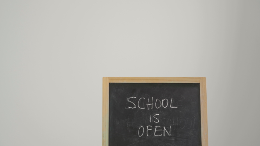 Little student behind blackboard written School is open