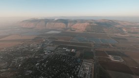 A peaceful morning hot air balloon voyage, the sun has just came up and some light clouds, mountains and valleys are visible underneath. a 4K video clip, Jezreel valley, Israel.