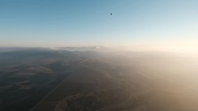A peaceful morning hot air balloon voyage, the sun has just woke up and some golden clouds, mountains and valleys are visible underneath. a 4K video clip, Jezreel valley, Israel.