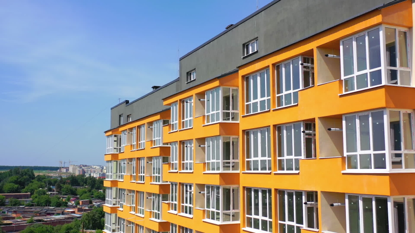 New multi storey in the city. Modern design of apartment building with orange walls with large balconies. Facade of luxury house for city residents.