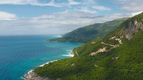 Drone flight over the green mountains of the Barahona Dominican Republic overlooking the blue Caribbean Sea. Summer trip to a tropical island.