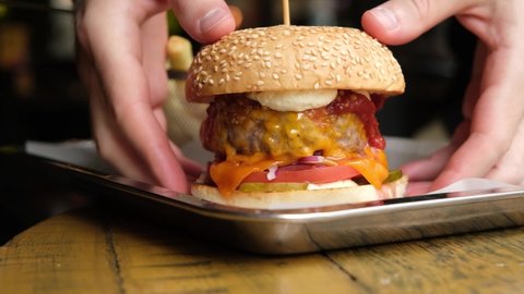 Male hands picking tasty juicy burger with cheese and sauce