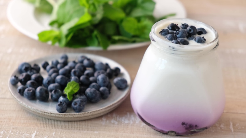 Yogurt with blueberries in glass jar. Taking spoonful of natural greek yogurt Royalty-Free Stock Footage #1079236340