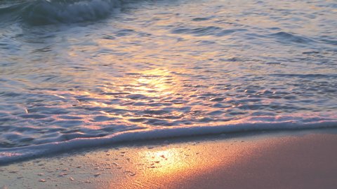 Sunset in Seaside, Santa Rosa Beach, Florida in panhandle with closeup of shore and gulf of mexico ocean waves and reflection of sun path in water surface