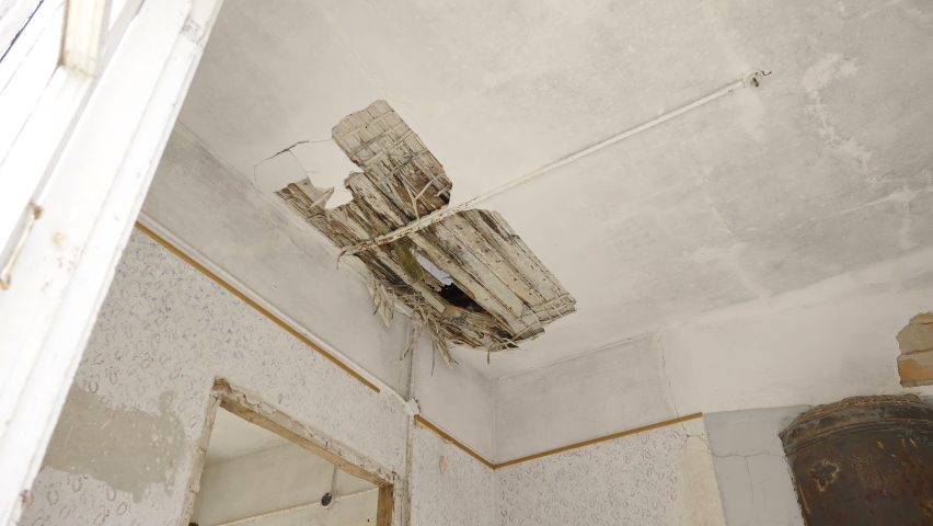 The broken wood of the ceiling from the abandoned house with the pieces hanging around in Estonia