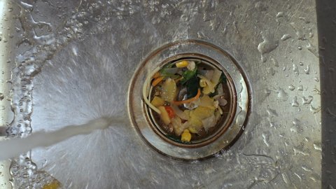 Dirty kitchen sink drain clogging up with food particles. Food waste leftower in draining water