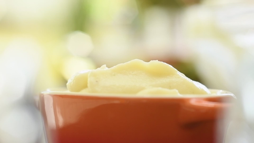 The cook serves mashed potato into a bowl.
