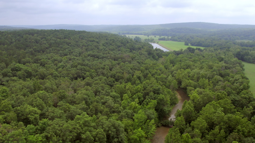 Pan of countryside in southern Missouri with lodge amongst trees.