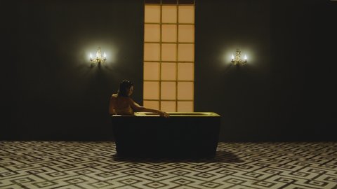 Beautiful, thin and sexy woman on bikini lying inside bathtub in luxury designed bathroom interior . Girl with long legs having bath moving and dancing . Side view slow motion . Sexual performance

