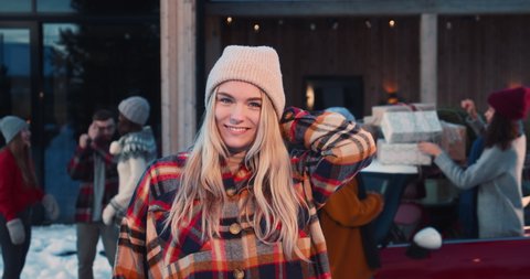 Excited beautiful happy young blonde woman in winter hat smiling at camera at fun Christmas friends party slow motion.