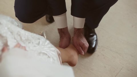 Man in suit with hairy hands gives massage to woman in awedding dress. Man with medical degree kneads the foot of woman legs in pantyhose. First aid.