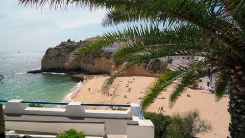 Beautiful view of the Portuguese Carvoeiro beach in summer with clear sea and sunbathing tourists. Shooting in motion with a stabilizer.