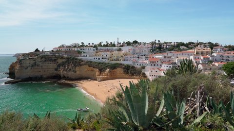 Beautiful view of the Portuguese Carvoeiro beach in summer with clear sea and sunbathing tourists. Shooting in motion with a stabilizer.