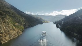 Aerial shot of boat floating in picturesque mountains landscape, Peso da Regua, Vila Real, Portugal, Europe. Birds eye view of Douro river surrounded agricultural area of grape plants, 4k footage