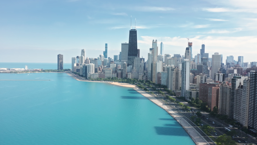 Cinematic aerial Chicago coastline with beach. Sunny summer day with copy space on blue green background. Travel business footage, drone 4K. Modern water front buildings with Michigan lake view, USA